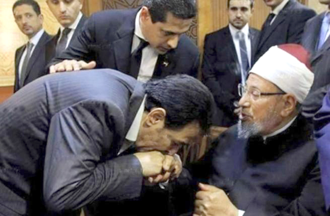 [ صورة شهيرة تطارد رمضان، يظهر فيها وهو ينحني ويقبل يد الشيخ الإخواني يوسف القرضاوي، المعروف بتحريضه على الدولة. 